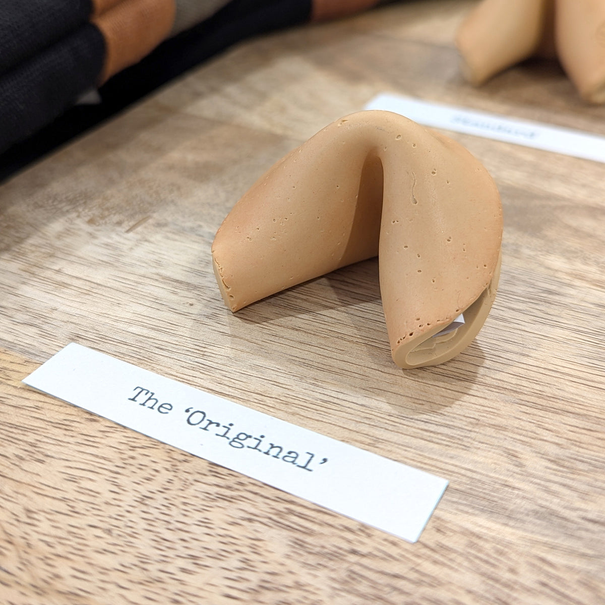 The ‘Original’ Smart Fortune Cookie on a wooden table beside its name card