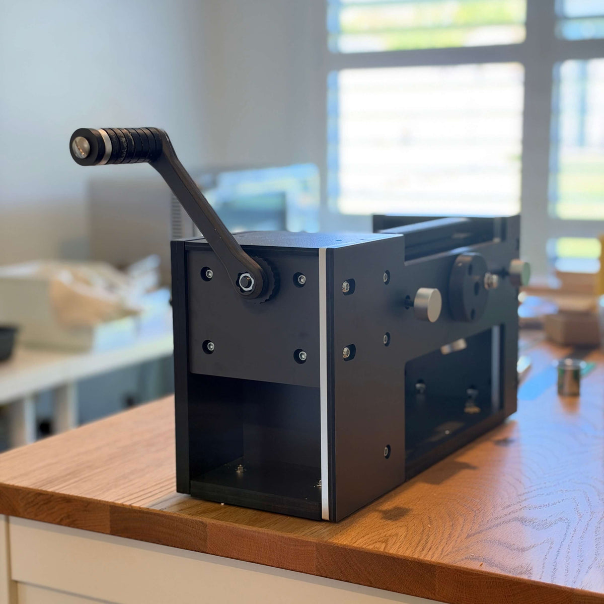 A hand-cranked clay conditioning machine on the studio bench